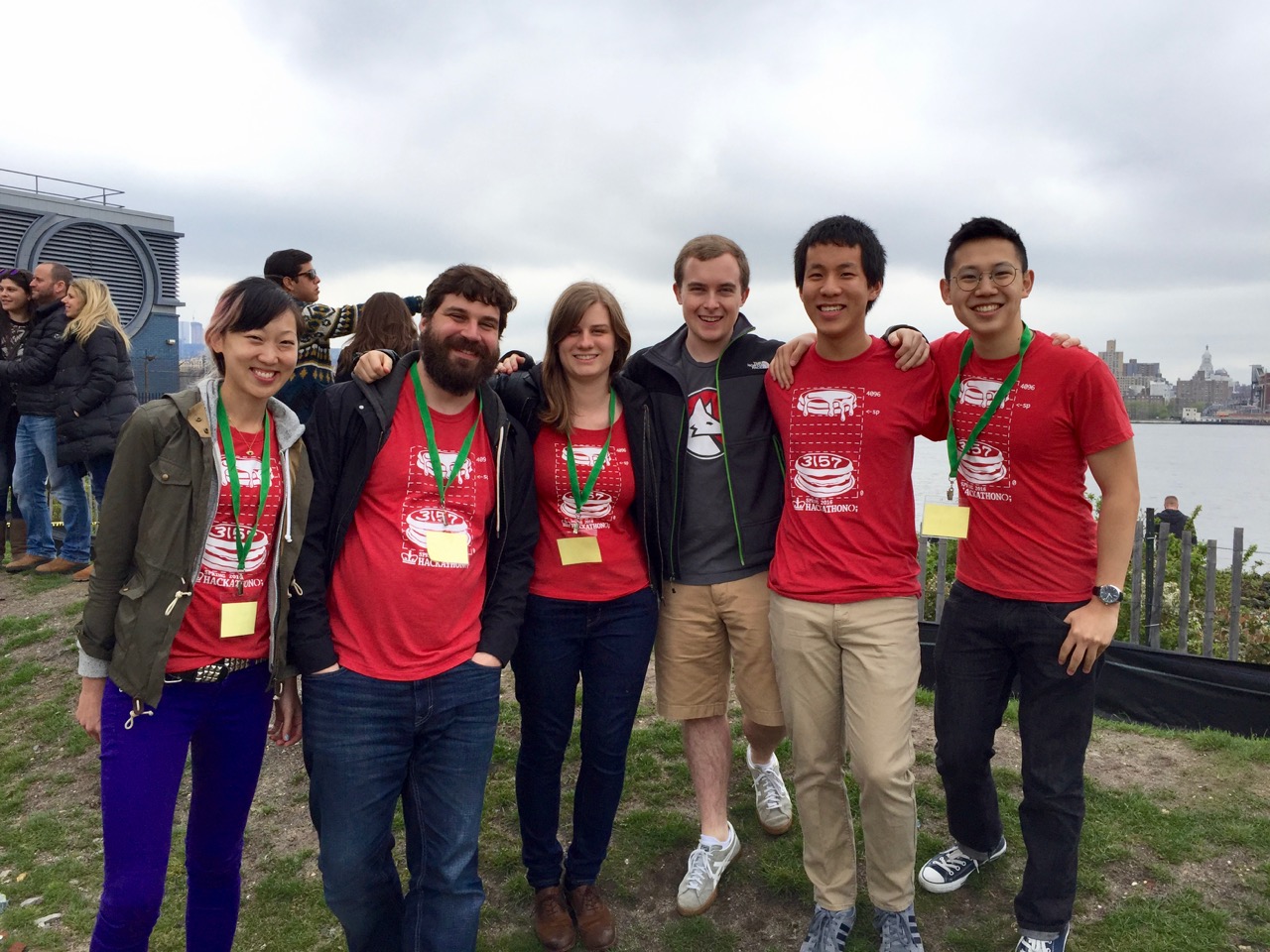 Five students with red shirts standing near water